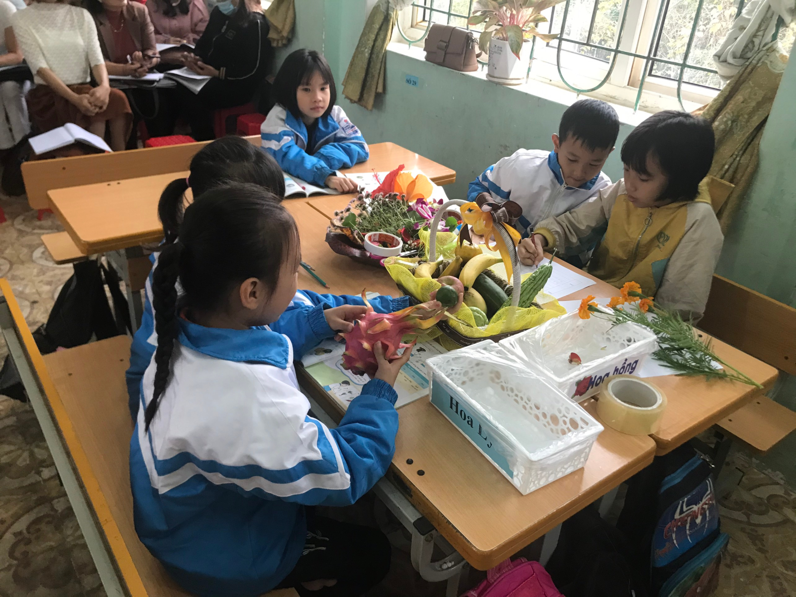 A group of children sitting at a table with flowers  Description automatically generated with low confidence